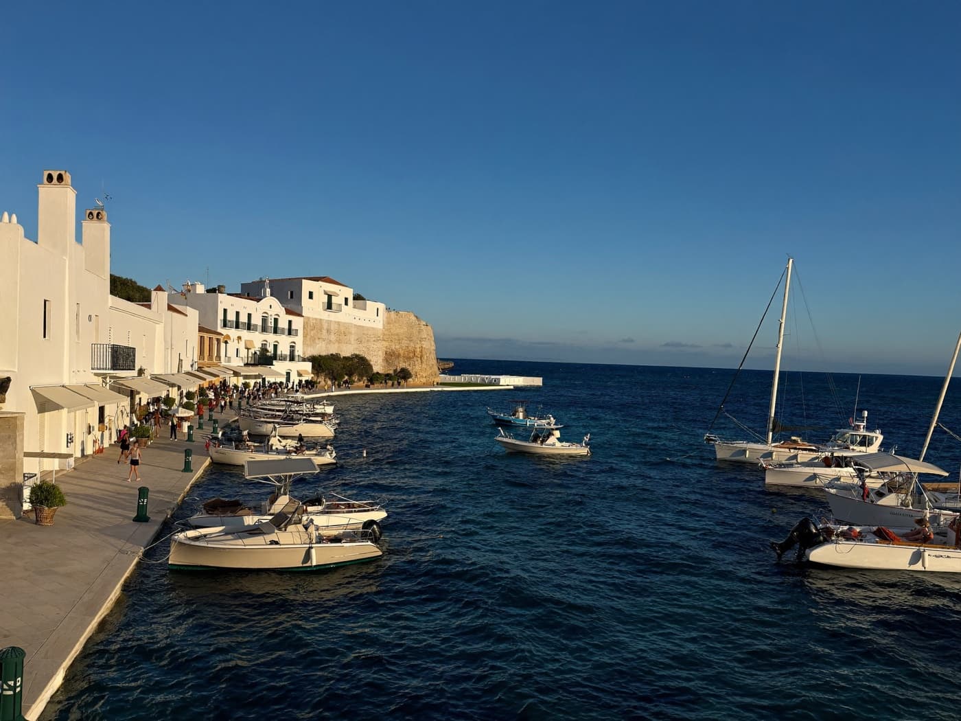 Mediterranean marina with white buildings and moored boats in golden afternoon light
